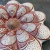 Flor de parede decorativa em cerâmica com detalhes em vermelho e branco, inspirada no Vale Jequitinhonha.