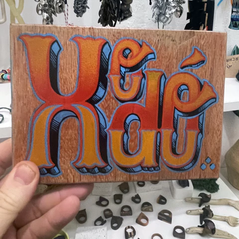 Placa de madeira com pintura colorida das palavras "Xodó" em estilo artístico