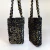 Bolsa shoulder bag de tecido preto com detalhes em paetês dourados e alças trançadas.