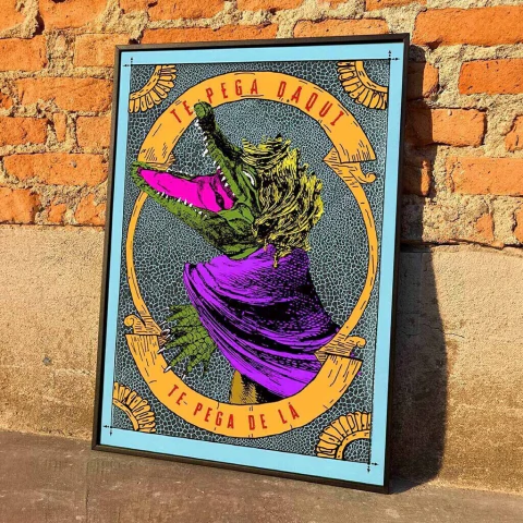 Quadro artístico de papel com ilustração colorida da personagem folclórica Cuca usando capa roxa e cabelo amarelo, com moldura preta, apoiado em parede de tijolos
