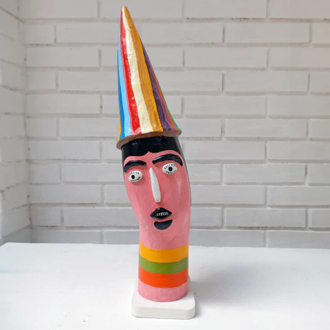 Escultura colorida representando uma figura humana com um chapéu listrado e expressões faciais distintas.