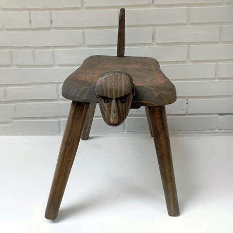 Banco de madeira com design de rosto de macaco, apresentando pernas longas e uma cauda.