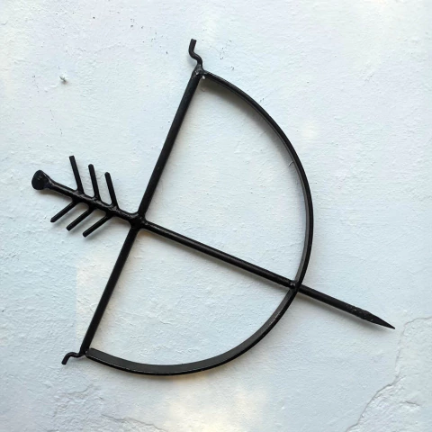 Um objeto decorativo de metal preto com formato de arco e flecha, montado na parede.