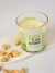 Vela aromática Pistacchio em copo de vidro transparente com rótulo branco e verde, acompanhada por pistaches com casca ao lado
