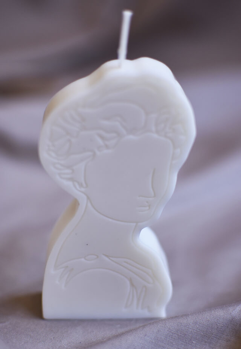 Vela branca decorativa no formato de retrato feminino estilizado com traços delicados