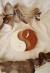 Vela decorativa em formato yin-yang nas cores off white e marrom, sobre tecido claro com folhas secas ao redor