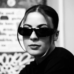 Mulher usando óculos de sol HYPE 2.0 com estilo moderno, em um ambiente urbano.