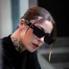 Modelo usando óculos de sol retangulares Double X, com detalhes de tatuagens visíveis no pescoço.