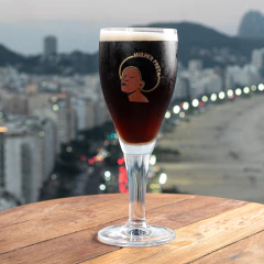 Taça de vidro com cerveja escura Harzer Mulher Preta em mesa de madeira com fundo desfocado de cidade à noite