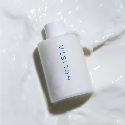 Botella de Glow Milk Esencia hidratante de Holista sobre fondo blanco, producto de skincare.