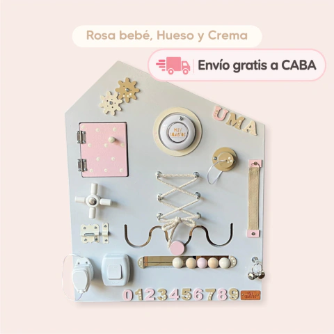 Tablero sensorial mediano en colores rosa bebé, hueso y crema con elementos interactivos como engranajes, cerraduras, botones y cordones para estimulación infantil.