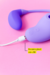 Vibrador Flex roxo com função de sucção, de vibração e carregamento USB. Produto em fundo rosa.