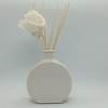 Difusor de varillas en un florero de cerámica blanca con flor decorativa