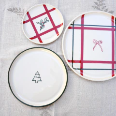 Plato navideño de cerámica artesanal de 18 cm con borde verde inglés pintado a mano y sello de arbolito de Navidad en el centro, sobre mantel de tela.