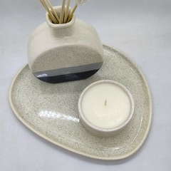 Florero de cerámica con vela aromática y plato de sitio