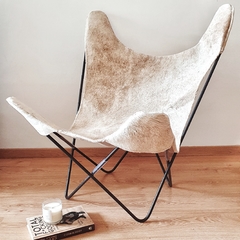 Sillón BKF de cuero de vaca, con estructura metálica, ubicado en un ambiente decorativo acogedor.