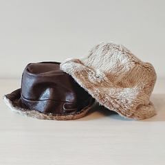 Sombreros de cuero en tonos marrón y beige, sobre una superficie clara.