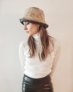 Sombrero de cuero Myrtos en una modelo con suéter blanco y falda de cuero negra, posando de perfil.