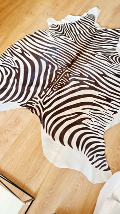 Alfombra de cuero de vaca con estampado de cebra sobre un piso de madera.