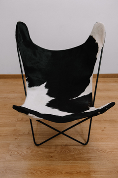 Sillón BKF de cuero de vaca con diseño en blanco y negro, sobre un fondo de madera clara.