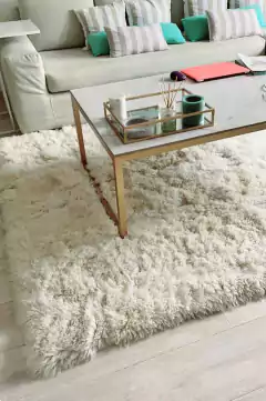 Alfombra de cuero de oveja Sarakina en un ambiente moderno, con un sofá y una mesa de café sobre ella.