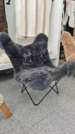 Sillón BKF de cuero de oveja en color gris, con estructura metálica y diseño moderno, ubicado en un ambiente decorativo.