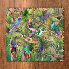 Paño para gafas con ilustraciones de colibríes de colores vibrantes sobre un fondo rosa y hojas verdes.
