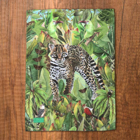 Paño de cocina ecológico con diseño de un ocelote en un entorno natural tropical, rodeado de hojas y aves.