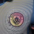 Logotipo do Manchester City em destaque na camisa amarela e azul turquesa da versão jogador para a temporada 24/25.