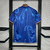 Camisa de futebol azul com padrão fluido nas costas, pendurada em um suporte. Detalhes em laranja nas mangas.