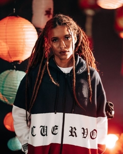 O Flag Hoodie possui um punho personalizado com abertura para encaixar o dedo. O capuz é duplo, feito com próprio tecido da peça, o que eleva a qualidade do produto. Conta com um cadarço tubular em nylon para a regulagem. Em sua barra, a ribana dupla ajud