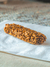 Barra de cereal hecha de granos y frutos secos sobre una servilleta blanca.