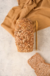 Pan vegano de 7 cereales con corteza de semillas, acompañado de rebanadas sobre una superficie clara.