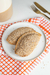 Dos empanadas integrales sin sal, cubiertas con semillas de sésamo, sobre un plato blanco y un paño de cocina a rayas naranjas y blancas.