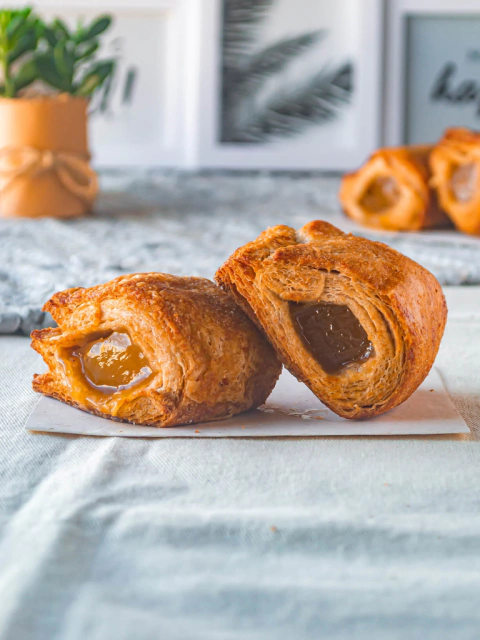 Dos libritos de batata recién horneados, mostrando su interior relleno de dulce de batata, sobre un fondo claro.