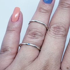 na mão par de aliança em prata com 2mm polida abaulada e com uma pedra de zircônia azul