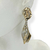 Brinco Bijuteria Dourado - Pino oval martelado + concha pendurada - comprar online