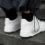 Zapatos deportivos blancos modelo Trust One, vistos desde atrás mientras una persona sube escaleras.