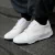 Zapatos deportivos blancos modelo Trust One, con detalles de diseño moderno y suela negra.