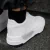 Zapatillas blancas modelo Trust One, vistas desde atrás, con detalles en la parte lateral y suela negra.