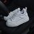 Zapatos deportivos blancos con suela gruesa sobre un asiento de auto.
