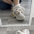Imagen de zapatillas Aglet en tonos claros, con detalles en dorado y una suela gruesa, vistas en un espejo.