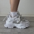 Zapatillas Aglet blancas con detalles en gris, vistas de perfil sobre un fondo claro.
