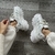 Zapatillas deportivas blancas con detalles en relieve, vistas desde arriba, sobre un piso de madera.