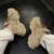 Un par de zapatillas deportivas de color beige con detalles texturizados, vistas desde arriba sobre un fondo oscuro.