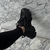 Zapato deportivo negro sobre un fondo de mármol claro.
