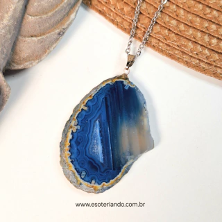 Colar com chapa de ágata azul clara, destacando suas camadas e tonalidades, sobre fundo claro.