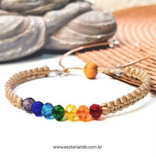 Pulseira de macramê com contas de vidro facetado nas cores dos chakras, ajustável, em fundo de palha.