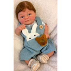 Bebê reborn menino realista de silicone sólido com cabelo castanho, vestido com jardineira azul e camiseta listrada, segurando brinquedos