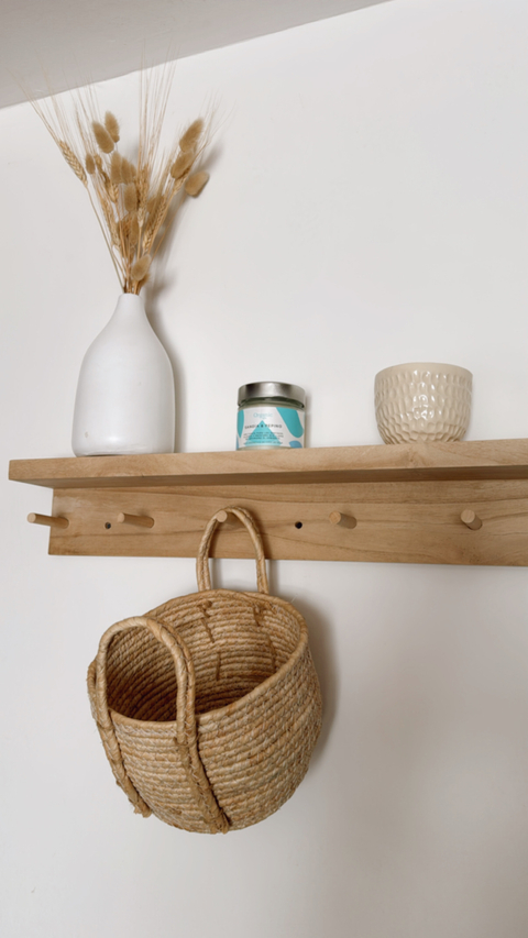 Estante Perchero Bayo Kiri de madera con decoración, incluye una cesta de mimbre, un jarrón blanco y velas.